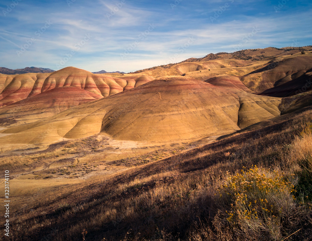 Breathing and colorful Painted Hills covered in red, tan, black, orange, and yellow stripes on a partly cloudy autumn day at the John Day Fossil Beds in Mitchell Oregon