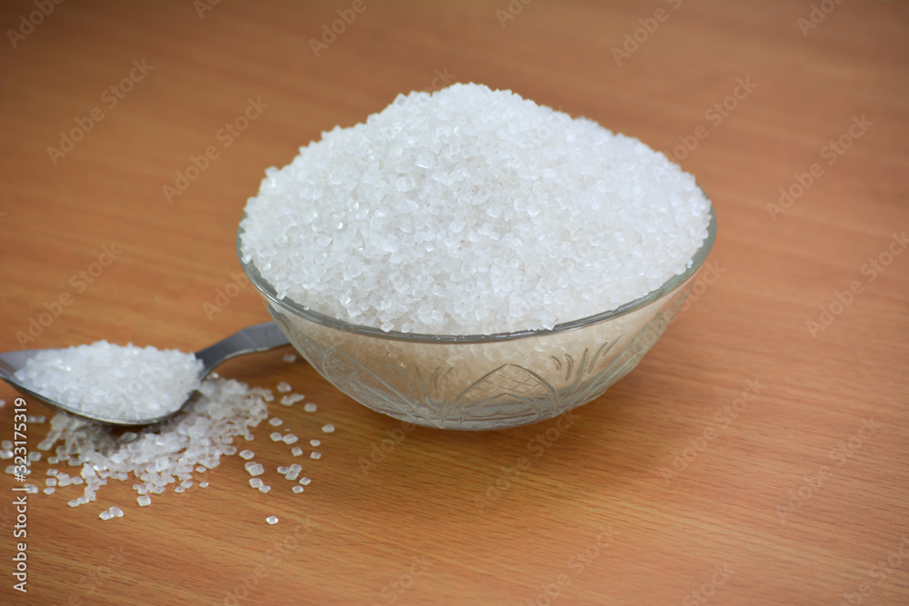 Sugar in glass bowl on wooden background Sugar in glass bowl on wooden background