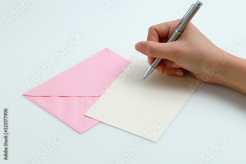 Woman's hands writing in blank note card with envelope