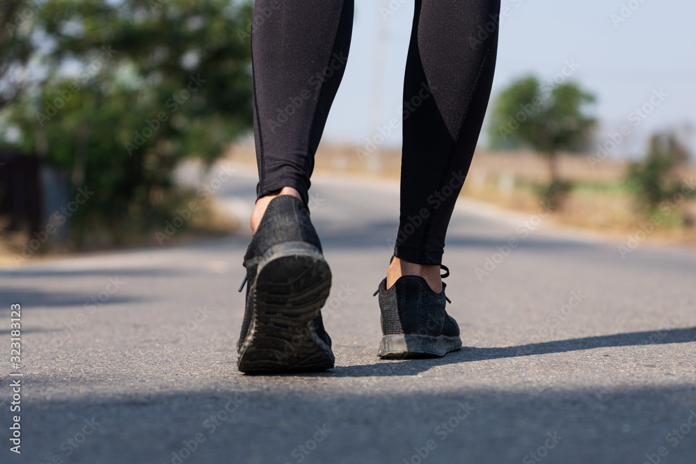 Close up Athlete running woman wearing Exercise pants and running shoe on the road,Runner woman traning in the morning.Walking for warm up her muscle. Close up Athlete running woman wearing Exercise pants and running shoe on the road,Runner woman traning in the morning.Walking for warm up her muscle.