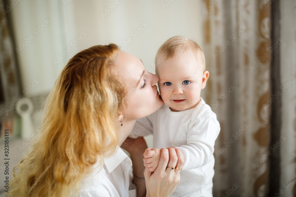 Caucasian blonde Mom hugs and kisses baby 7 months Caucasian blonde Mom hugs and kisses baby 7 months