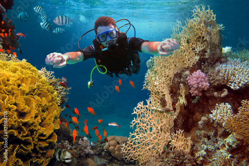 The happy man dives among corals and fishes in the ocean