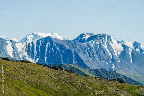 Awesome aerial view to big snowy rocky mountains and great glacier under blue sky. Wonderful vivid highland scenery with giant mountains with snow. Beautiful alpine landscape with glacial mountains.