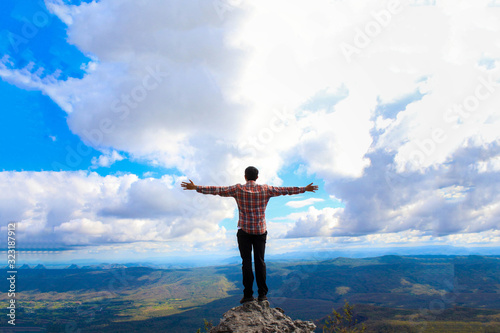 A man stand on the top mountain cliff and acting of freedom life style travel trip successful background textures concept.