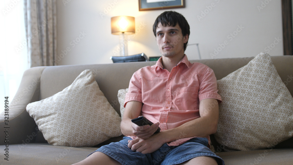 Obraz premium Young man relaxing and watching tv in a living room