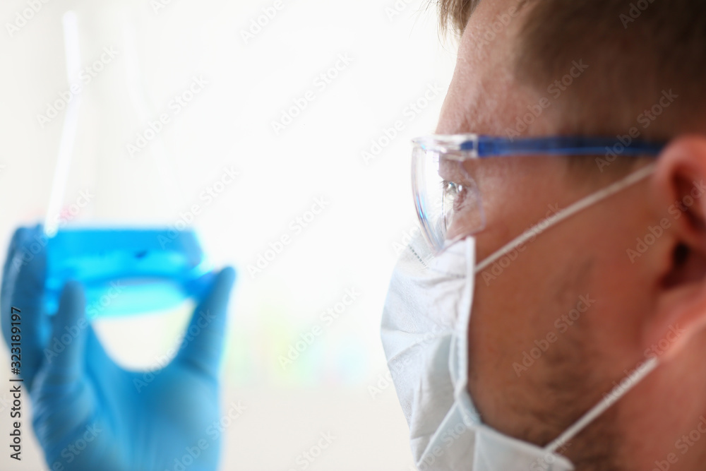 A male chemist holds test tube of glass in his hand overflows a liquid solution of potassium permanganate conducts an analysis reaction takes various versions of reagents using chemical manufacturing. A male chemist holds test tube of glass in his hand overflows a liquid solution of potassium permanganate conducts an analysis reaction takes various versions of reagents using chemical manufacturing.