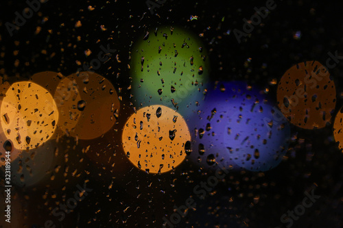 Blurred background of the night city rain drops on glass