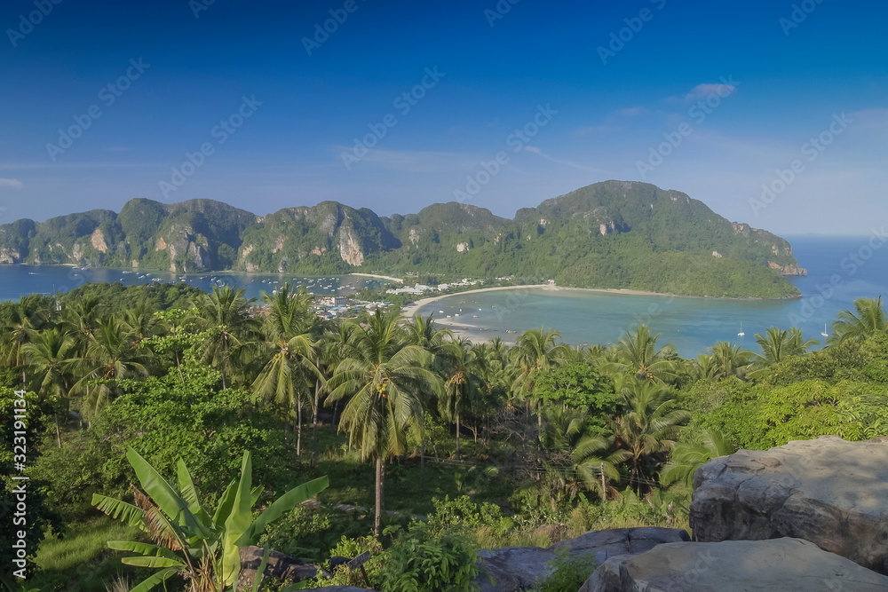 Mountain view panoramic morning of coconut trees, long beach and blue-green sea with green mountains and blue sky background, top view point Phi Phi Don island, Krabi, southern of Thailand.