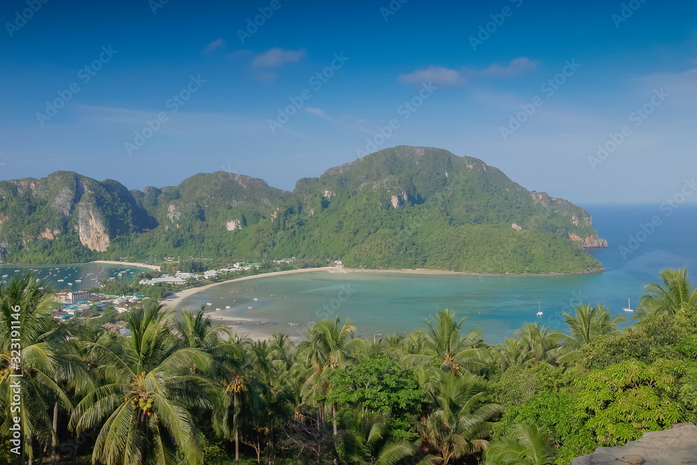 Mountain view panoramic morning of coconut trees, long beach and blue-green sea with green mountains and blue sky background, top view point Phi Phi Don island, Krabi, southern of Thailand.