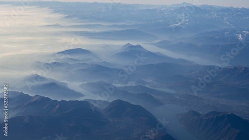 Aerial view of the smog and fog that covers the Po Valley in Italy and the first mountains of the Alps. Landscape from airplane window. Pollution due to low rain and no wind
