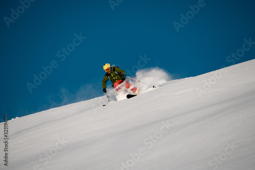 Male skier slides down on the mountain side
