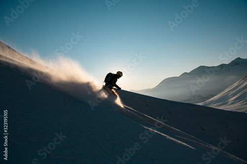 Obraz na płótnie Silhouette of male skier rides down from the snowy hill top