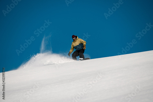 Male freerider slides down on the mountain side
