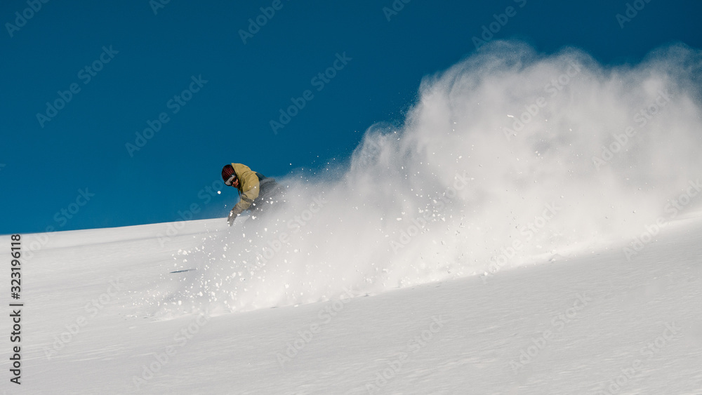 Male freerider slides down the snowy mountain slope