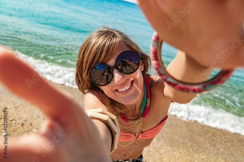Smiling girl making selfie on a sunny beach.