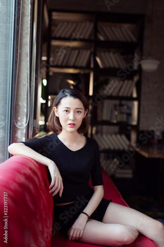 sexy woman sitting on red leather sofa,looking at camera. photo