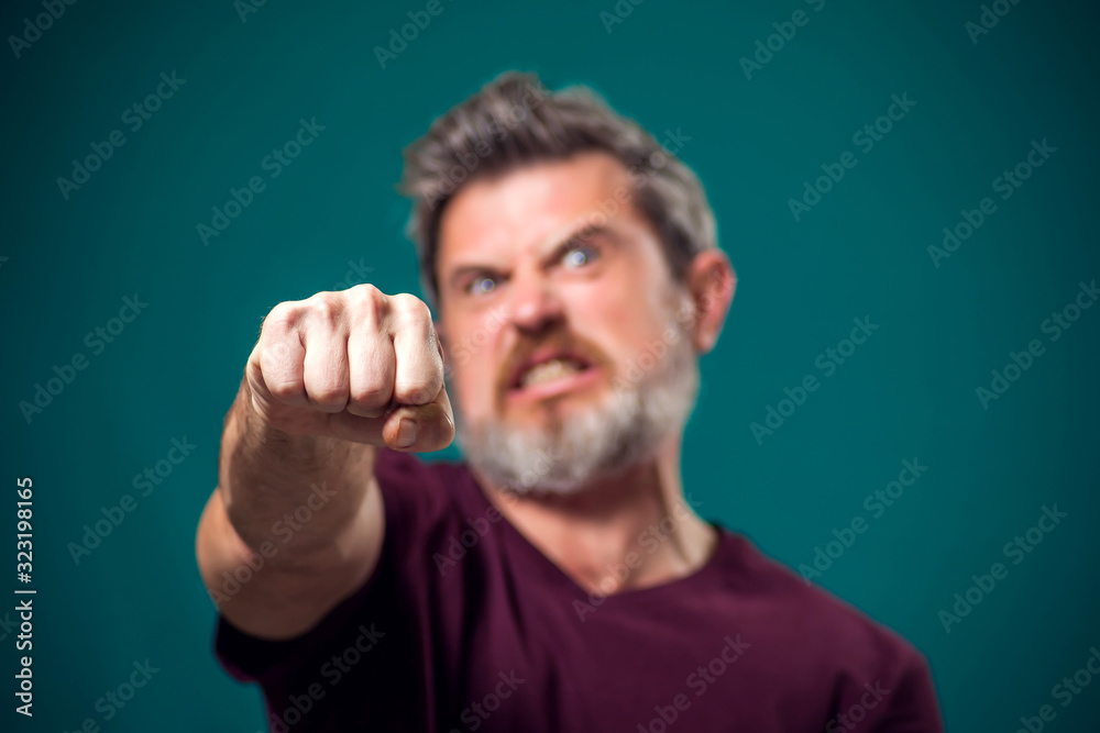 A portrait of bearded angry man showing fist at camera. People and emotions concept A portrait of bearded angry man showing fist at camera. People and emotions concept