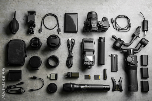 Flat lay composition with camera and video production equipment on light grey stone background photo