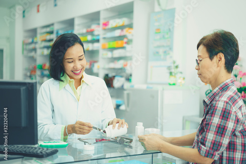 illness asia patient women and pharmacist or medicine, pharmaceutics, health care and people concept. Pharmacist discusses prescription medication with illness asian patient senior women or customer