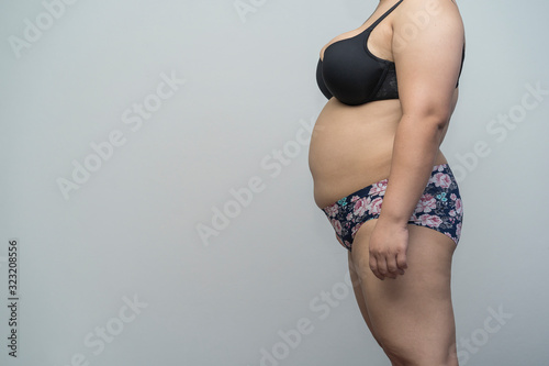 side view of fat Asian woman or Patient Medical Check up and cellulite of abdomen, waist cause of fatty weight. concept exercise, beauty, overweight or body firming gel,cream product or liposuction