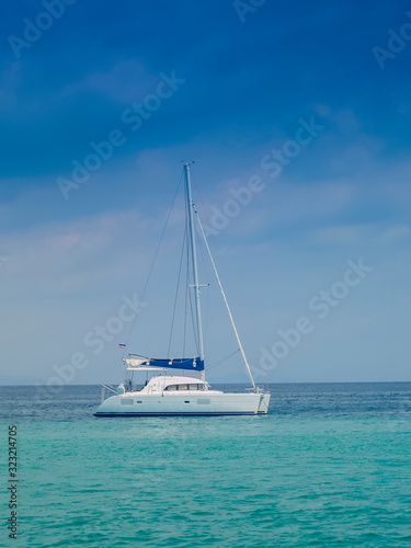 Sea view of a white yacht sailing in blue-green sea with cloudy and blue sky background, Phi Phi islands, Krabi, southern of Thailand.