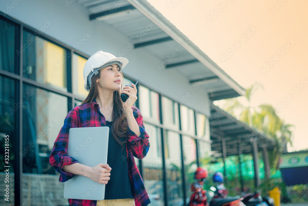 A beautiful businesswoman is talking on the radio with a building structure analyst and her hand is on a portable computer. A beautiful businesswoman is talking on the radio with a building structure analyst and her hand is on a portable computer.