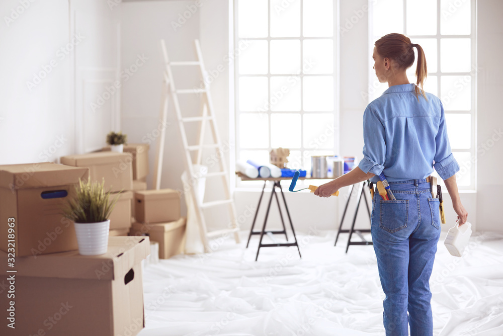 Happy woman paints wall with roller at home Happy woman paints wall with roller at home