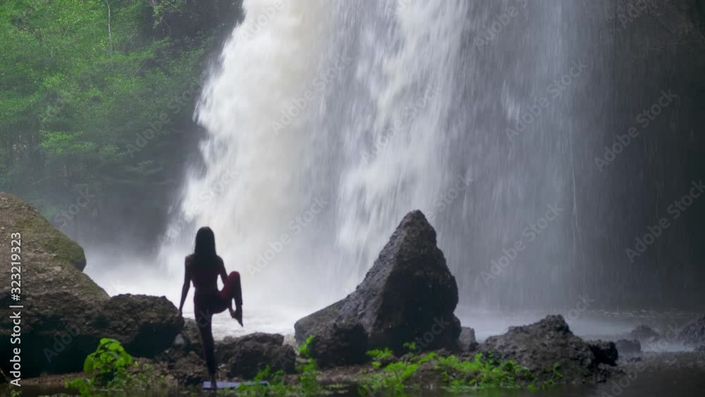 Asian woman practicing or doing yoga at the waterfall. Beautiful Landscape, Natural background, Thailand. Female professional yoga Asian woman practicing or doing yoga at the waterfall. Beautiful Landscape, Natural background, Thailand. Female professional yoga