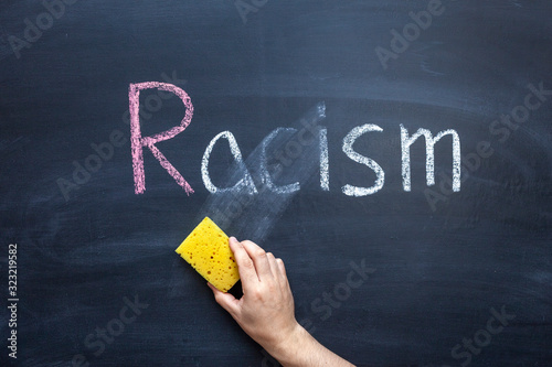 The teacher's hand erases the word Racism from the chalkboard. photo