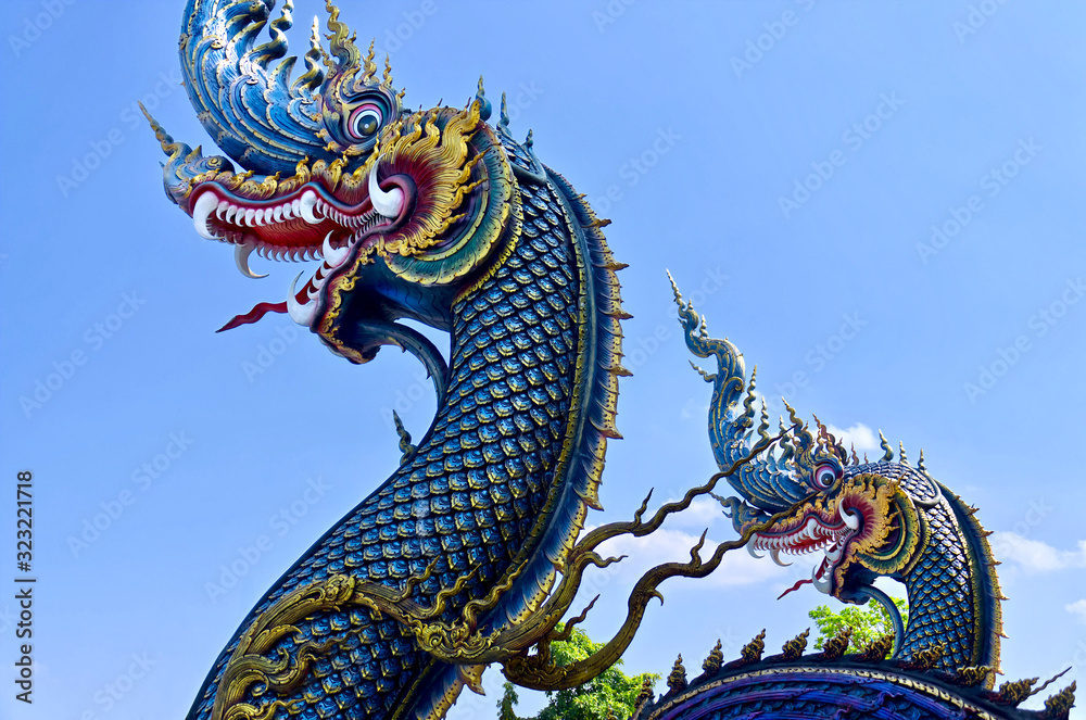 Fototapeta premium Beautiful blue naga sculpture (Thai dragon) on the blue sky background. Unique Blue Temple (Wat Rong Suea Ten)