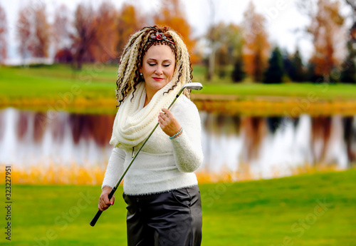 Cute girl with curly hair with a golf club in hands on a golf course in Riga, Latvia. Concept - healthy lifestyle.