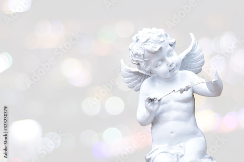 White cupid statue isolated with soft bokeh backdrop.