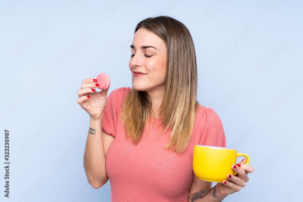 Φωτογραφία Young blonde woman over isolated blue background holding colorful French macaron