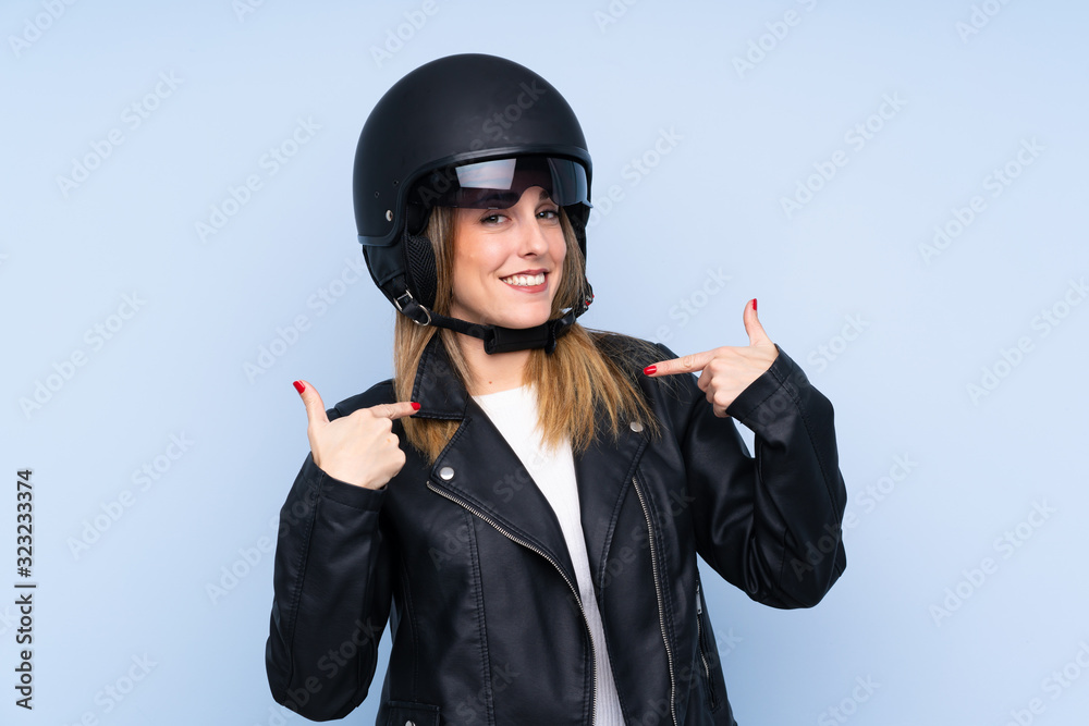 Young blonde woman with a motorcycle helmet over isolated blue background Young blonde woman with a motorcycle helmet over isolated blue background