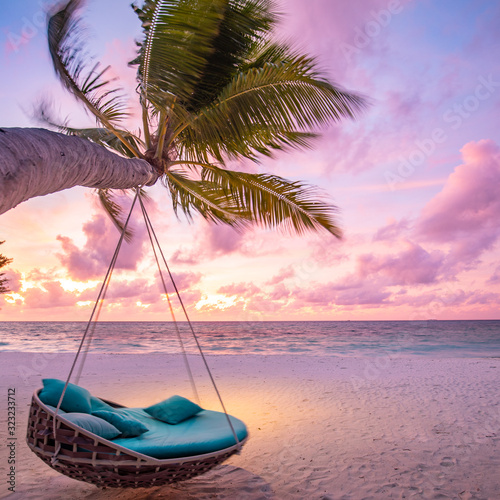 Tropical sunset beach background as summer landscape panorama with beach swing or hammock and white sand and calm sea beach banner. Perfect beach scene vacation or summer holiday concept © icemanphotos