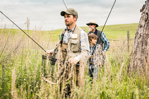 Grandfather, father and grandson walking to stream to go flyfishing. Red Lodge, Montana, USA photo