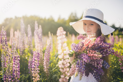 Beautiful girl in a white dress and hat in a field of flowers