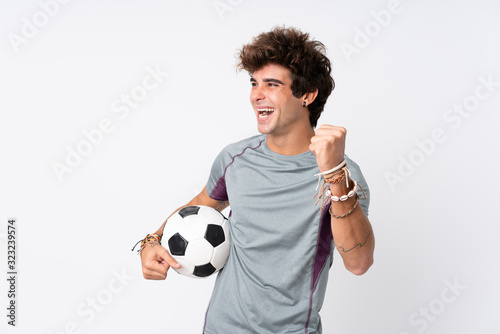 Young caucasian man over isolated white background with soccer ball celebrating a victory