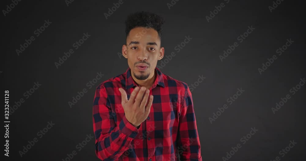 portrait of smiling african man in shirt sends air kisses at camera on dark background portrait of smiling african man in shirt sends air kisses at camera on dark background