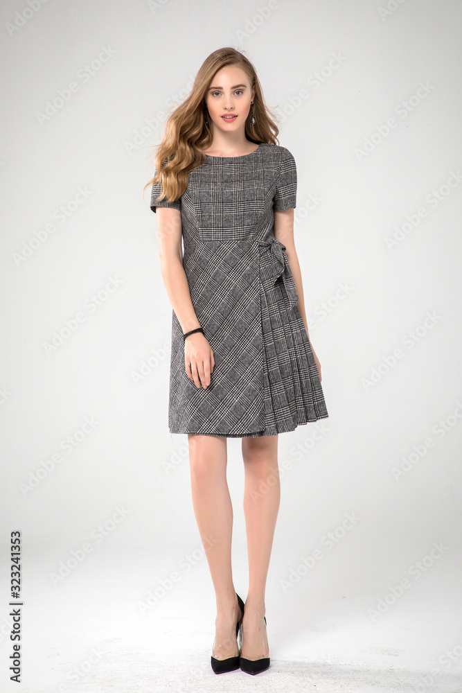 cute fashion model posing in pleated gray dress. white background . standing. studio shot. cute fashion model posing in pleated gray dress. white background . standing. studio shot.