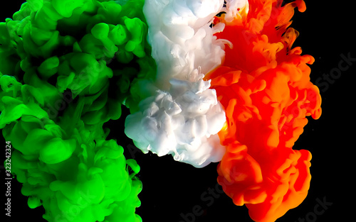 Flag of Ireland made of color ink on a black background. Green, white and orange watercolor ink in water.