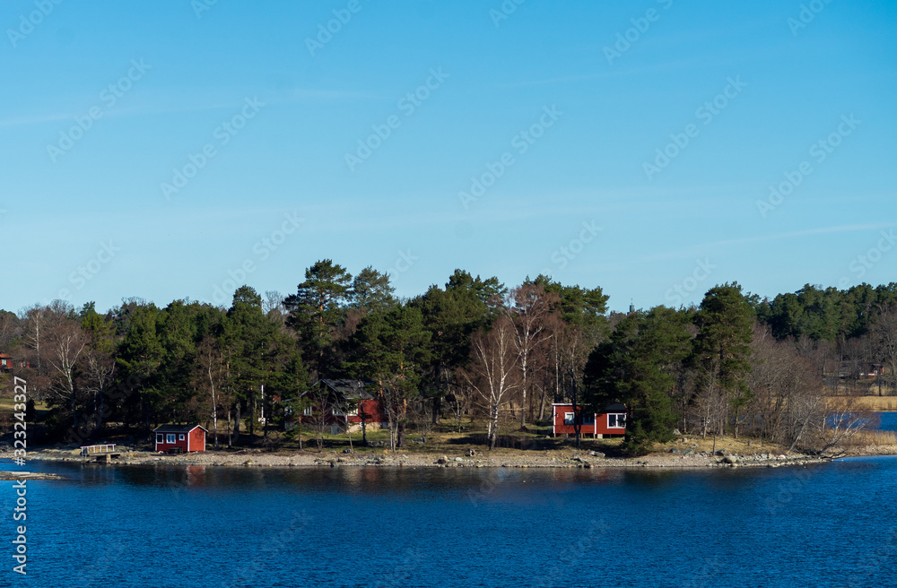 Picturesque summer houses painted in traditional falun red on dwellings island of the Stockholm archipelago in the Baltic Sea in the early morning. Picturesque summer houses painted in traditional falun red on dwellings island of the Stockholm archipelago in the Baltic Sea in the early morning.