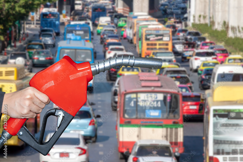 Fuel nozzle red separated from road traffic background. Fuel nozzle red separated from road traffic background.