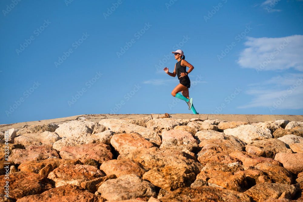 Fototapeta premium outdoors fitness lifestyle portrait of young attractive and athletic woman in compression running socks jogging happy on city park doing intervals workout in athlete training