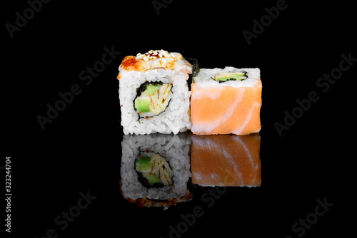 roll with salmon on a black background with insulation and reflection