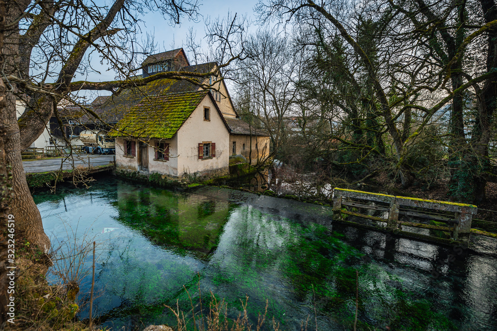 Reflection of an old mossy house in a green river in Blaubeuren.