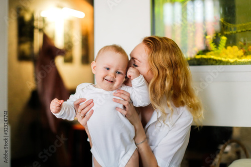 Happy baby boy having fun with mother on her hands