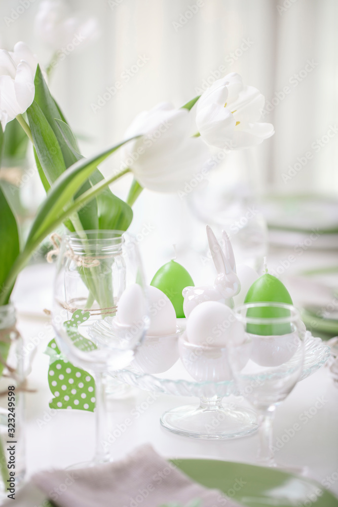 Decor and table setting of the Easter table with white tulips and dishes of green and white color. Easter decor in the form of Easter bunnies green color with white polka dots. Decor and table setting of the Easter table with white tulips and dishes of green and white color. Easter decor in the form of Easter bunnies green color with white polka dots.