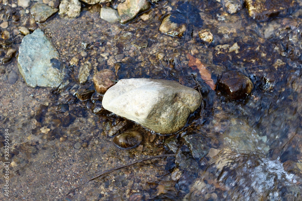 The rocky surface in the flowing creek water.