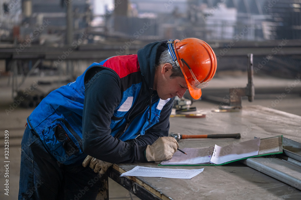 The builder studies the drawings on the construction site. The builder studies the drawings on the construction site.